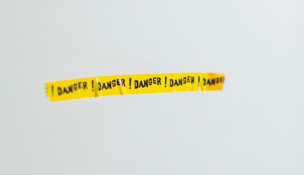 white wall with yellow danger! tape on it