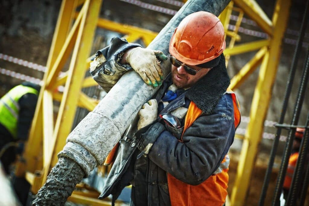 construction worker with a hard hat on holding a large pipe