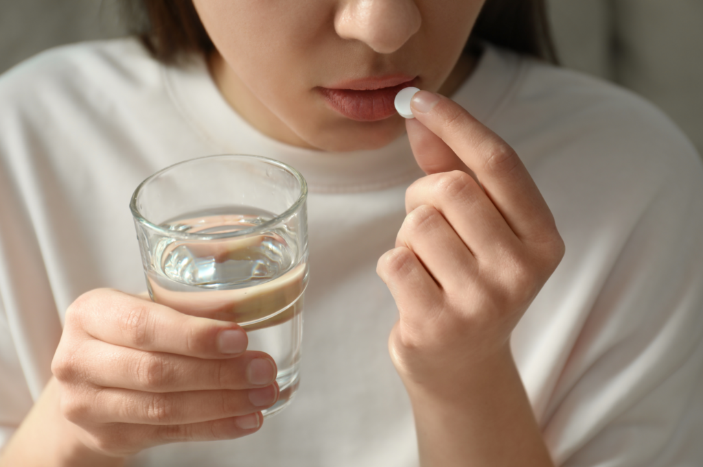 Woman holding a glass of water, about to take a synthetic opioid, depicting medication use.