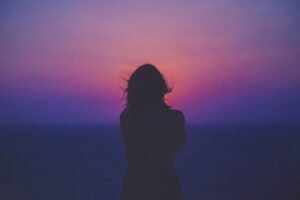 silhouette of a woman with a pink and purple sunset in the background