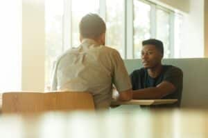 A man engaging in a conversation with a counselor discussing treatment options with person first language, emphasizing the individual's identity beyond their experience with addiction.