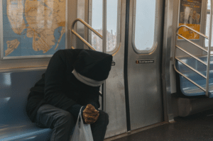Man sitting alone on a subway train, looking down, reflecting the emotional weight of addiction and the important of stigma reduction.