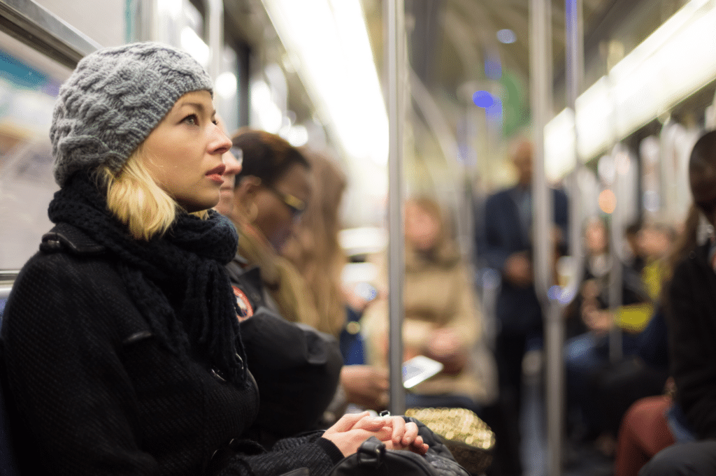 A woman sitting on a subways, looking up thoughtfully, symbolizing contemplation and hope in context of stigma reduction and reducing the stigma of addiction.